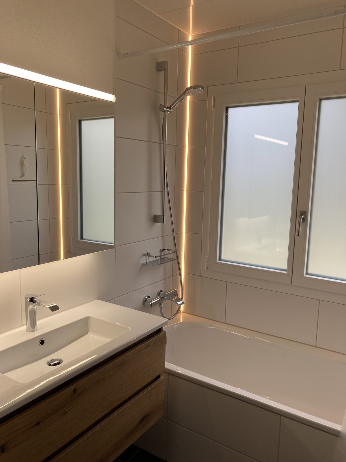 Badezimmer mit eingelassener LED-Beleuchtung entlang der Platten
